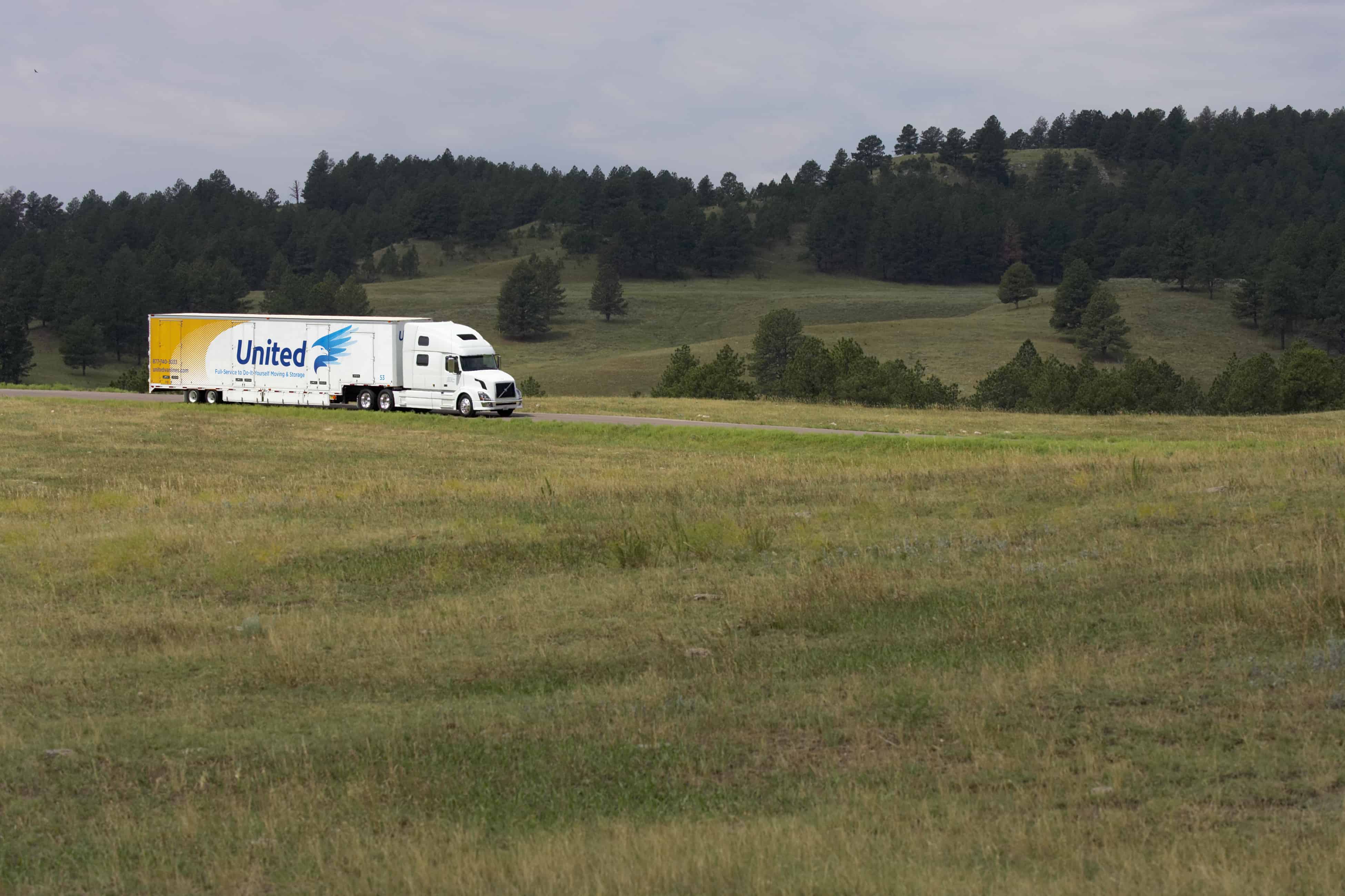 United moving truck on a rural road with trees and rolling hills in the background