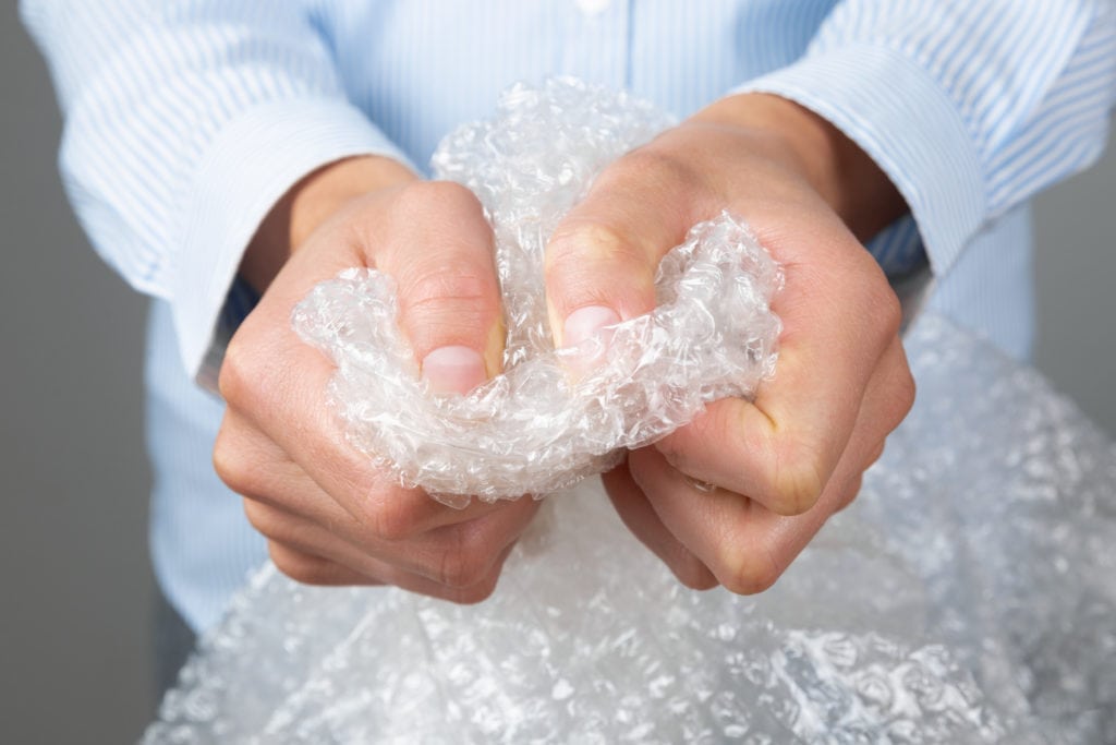 Person's hands squeezing bubble wrap moving supplies
