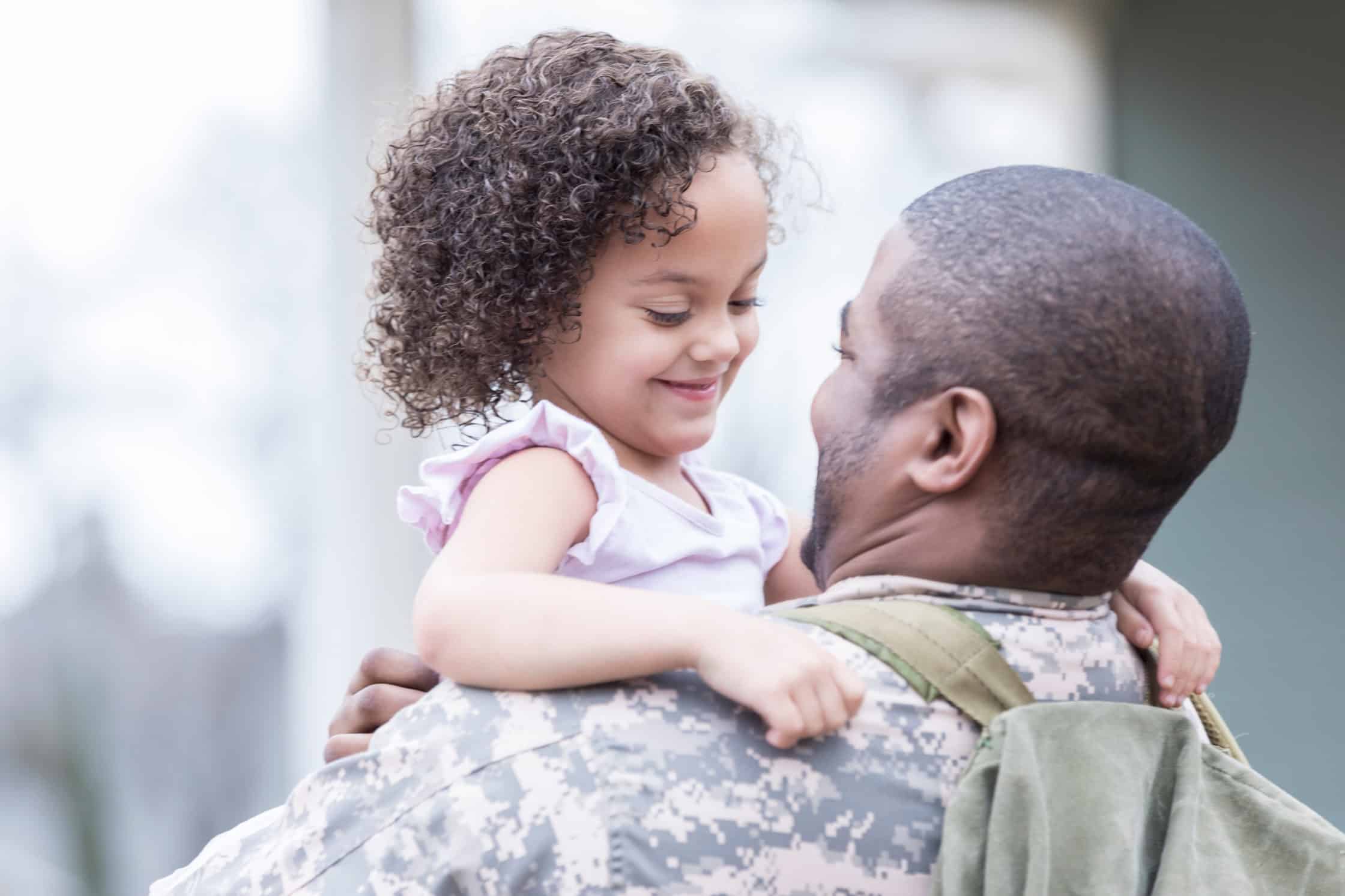 Military Moving Company - Smiling preschool age little girl hugs her dad. Her dad has returned from overseas military assignment. He is holding the little girl. - United Van Lines