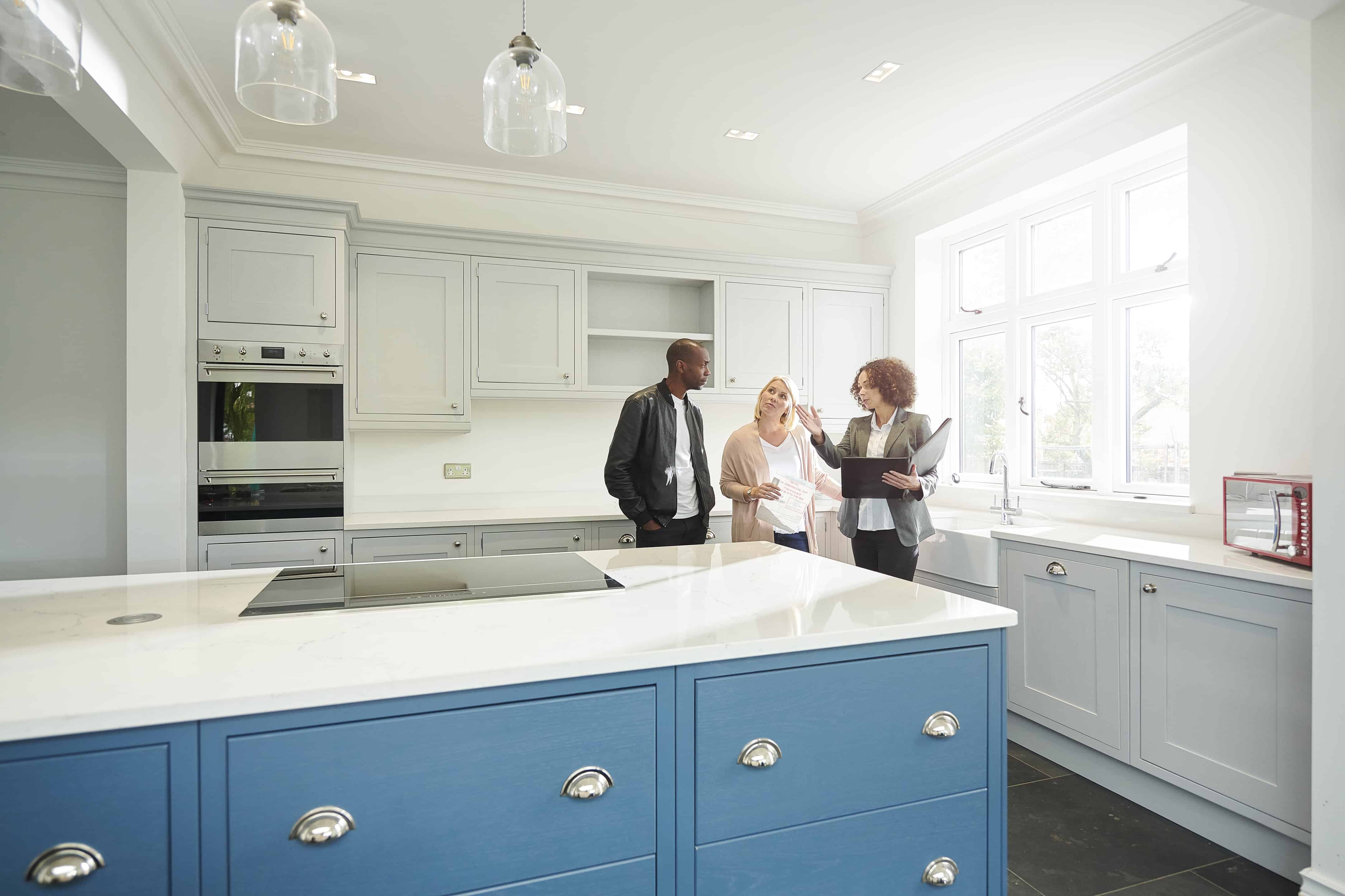 Real Estate Rewards - a saleswoman or estate agent shows a couple around a home with new kitchen - United Van Lines